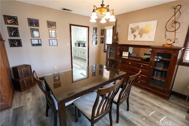 dining space featuring an inviting chandelier, hardwood / wood-style flooring, and a textured ceiling