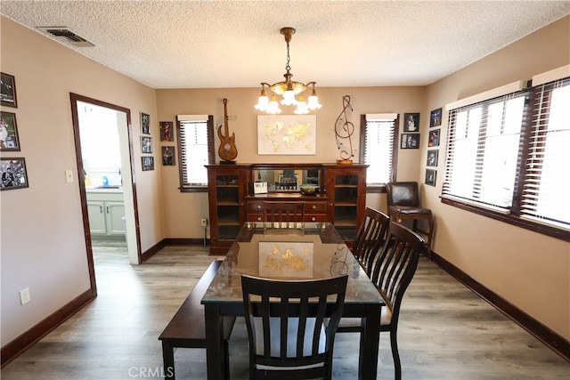 dining room with a notable chandelier, hardwood / wood-style floors, and a textured ceiling