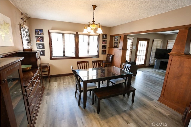 dining space with dark wood-type flooring, an inviting chandelier, and a textured ceiling