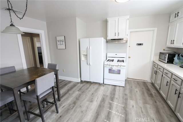 kitchen with white appliances, white cabinets, decorative light fixtures, and light wood-type flooring