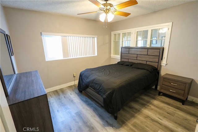 bedroom featuring a textured ceiling, ceiling fan, and dark hardwood / wood-style flooring