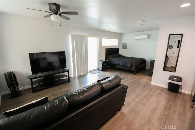 bedroom with light hardwood / wood-style floors, a wall mounted AC, and ceiling fan