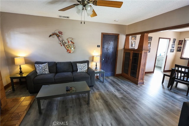 living room featuring ceiling fan, dark hardwood / wood-style floors, and a textured ceiling