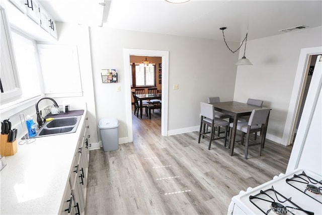 dining area with a notable chandelier, sink, and light hardwood / wood-style flooring