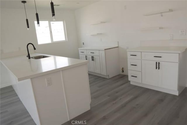 kitchen featuring dark wood-type flooring, white cabinets, sink, decorative light fixtures, and kitchen peninsula