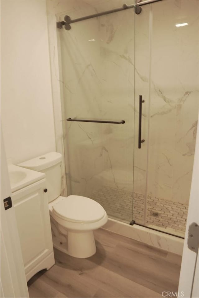 bathroom featuring walk in shower, toilet, vanity, and hardwood / wood-style flooring