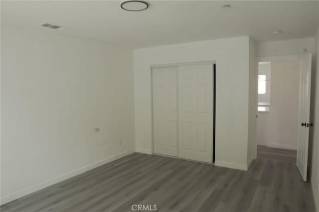 unfurnished bedroom featuring dark hardwood / wood-style floors and a closet