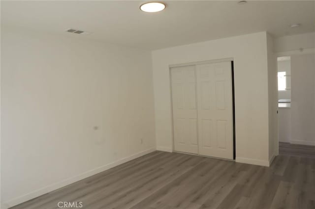 unfurnished bedroom with a closet and dark wood-type flooring