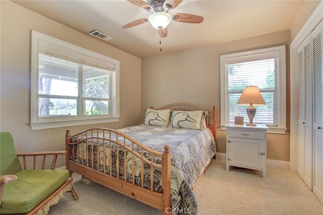 bedroom with light carpet, multiple windows, a closet, and ceiling fan