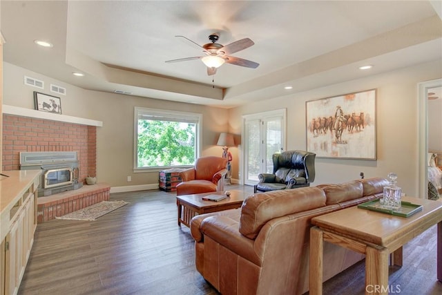 living room featuring ceiling fan, dark hardwood / wood-style floors, and a raised ceiling