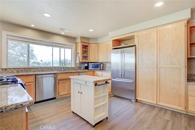 kitchen with sink, light wood-type flooring, stainless steel appliances, and a kitchen island