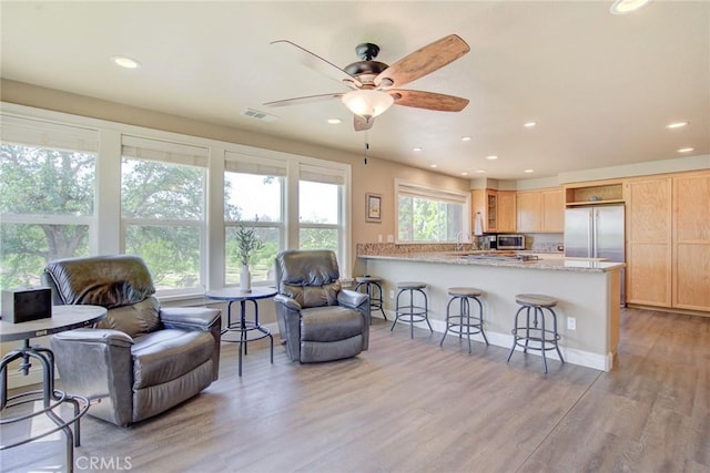 living room with ceiling fan, sink, and light hardwood / wood-style flooring