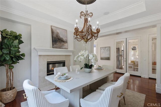 dining area featuring a notable chandelier, crown molding, dark wood-type flooring, and a premium fireplace