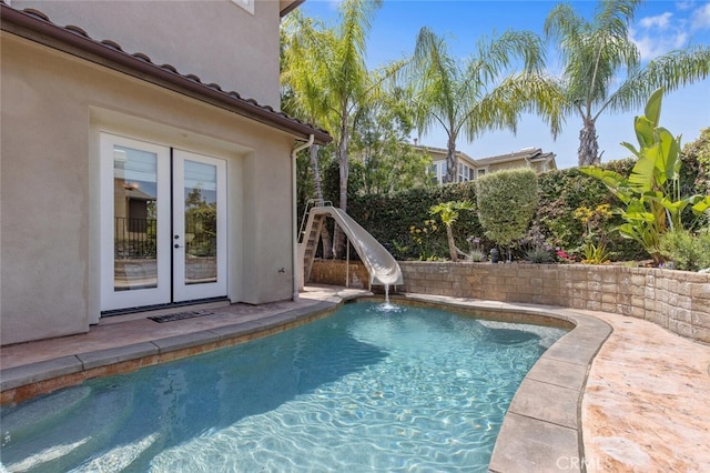 view of swimming pool featuring a water slide and french doors