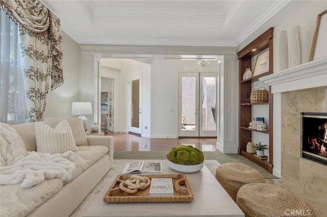 living room with french doors, a high end fireplace, crown molding, and a raised ceiling