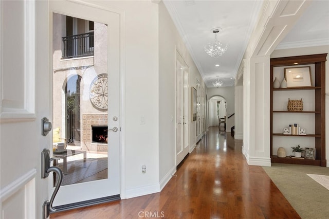 entrance foyer with hardwood / wood-style floors, crown molding, a fireplace, and a notable chandelier