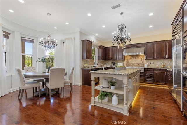 kitchen with a kitchen island, pendant lighting, an inviting chandelier, and wall chimney exhaust hood