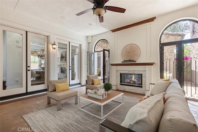 living room featuring a high end fireplace, french doors, and ceiling fan