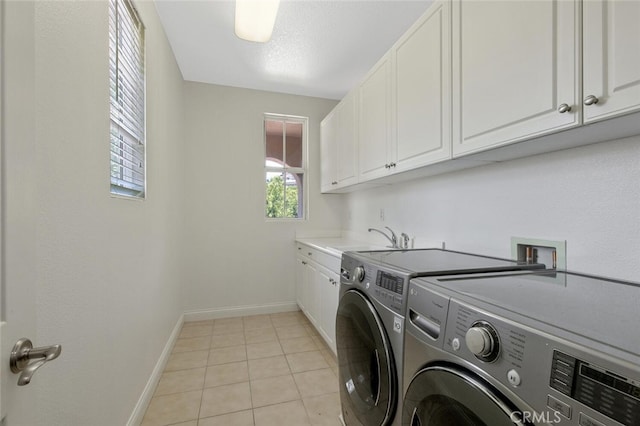 clothes washing area with cabinets, light tile patterned flooring, sink, and washer and clothes dryer