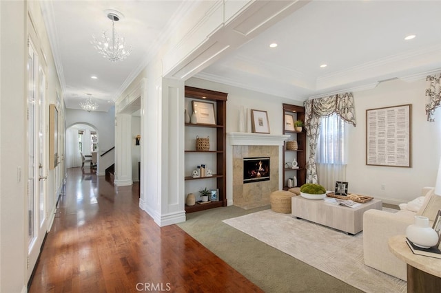 living room with an inviting chandelier, plenty of natural light, a tiled fireplace, and built in features