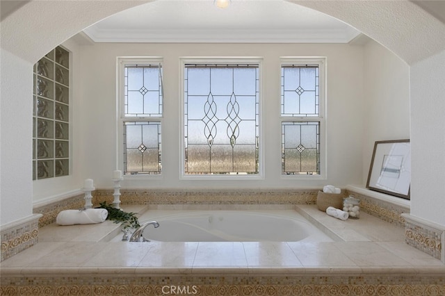 bathroom featuring crown molding, plenty of natural light, and tiled tub