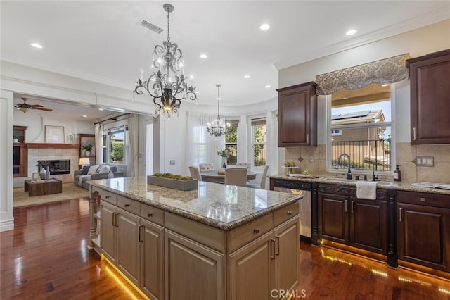 kitchen featuring a kitchen island, dark wood-type flooring, stainless steel dishwasher, and a fireplace