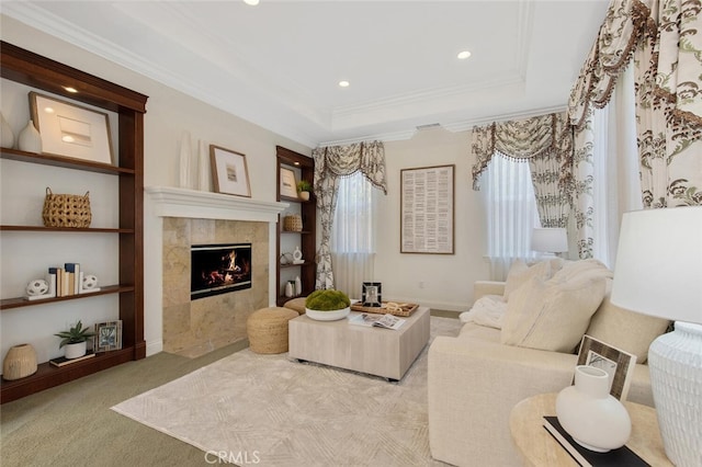 carpeted living room with a raised ceiling, ornamental molding, and a tile fireplace