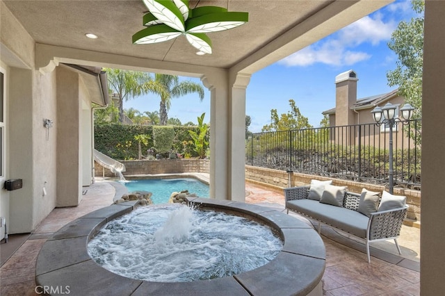 view of patio / terrace with a pool with hot tub and pool water feature