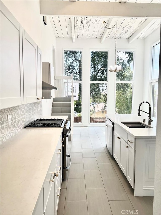 kitchen with sink, appliances with stainless steel finishes, hanging light fixtures, white cabinets, and decorative backsplash