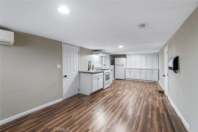 kitchen with a wall mounted AC, white cabinetry, white appliances, and dark hardwood / wood-style floors