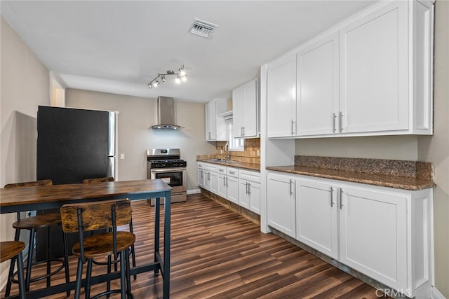 kitchen featuring dark hardwood / wood-style floors, tasteful backsplash, stainless steel appliances, wall chimney exhaust hood, and white cabinetry