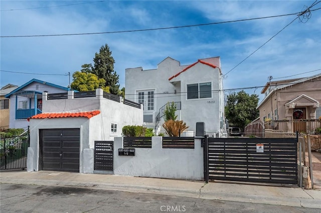 view of front of property with a garage, a fenced front yard, a gate, and stucco siding