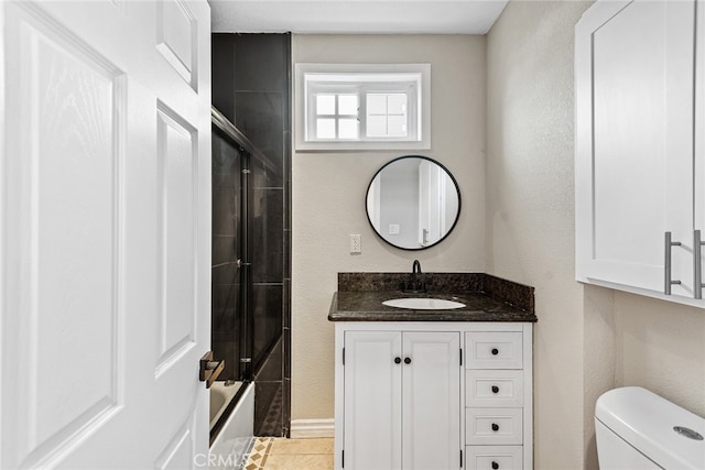 full bathroom featuring tile floors, bath / shower combo with glass door, vanity, and toilet