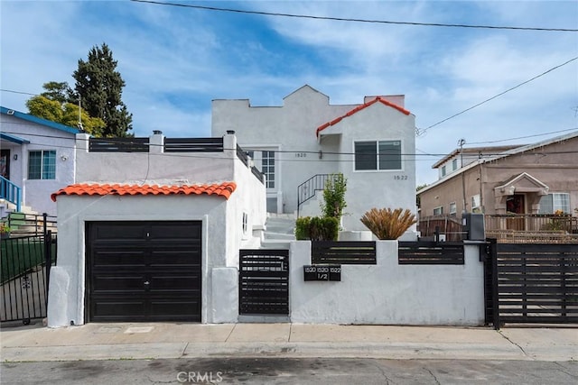 view of front of house with a fenced front yard, a tile roof, a gate, and stucco siding