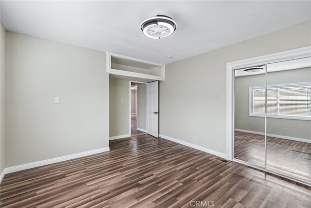 unfurnished bedroom featuring a closet and dark hardwood / wood-style flooring