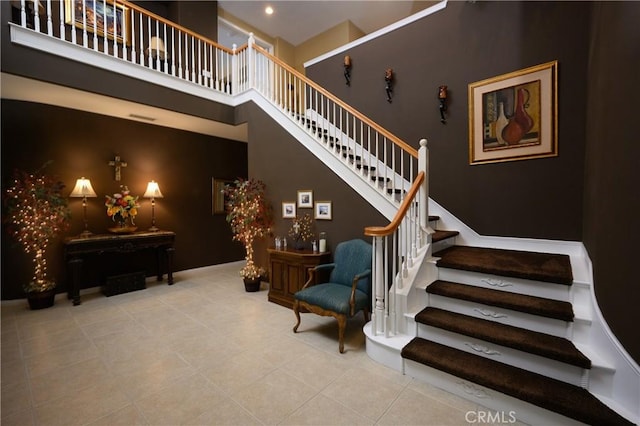 stairs featuring tile patterned floors and a high ceiling