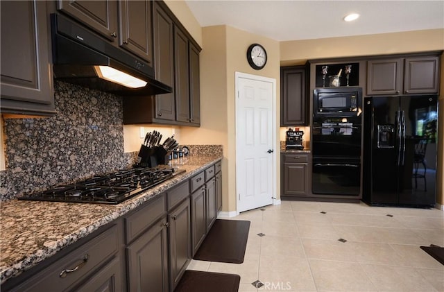 kitchen with black appliances, dark stone countertops, light tile patterned floors, tasteful backsplash, and dark brown cabinets