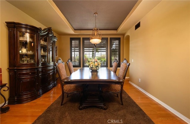 dining room with a tray ceiling and light hardwood / wood-style flooring