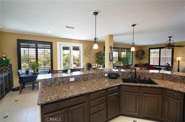 kitchen with pendant lighting, plenty of natural light, dark brown cabinetry, and sink