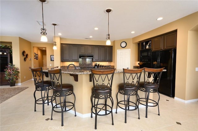 kitchen with a kitchen breakfast bar, stone counters, dark brown cabinets, and black appliances