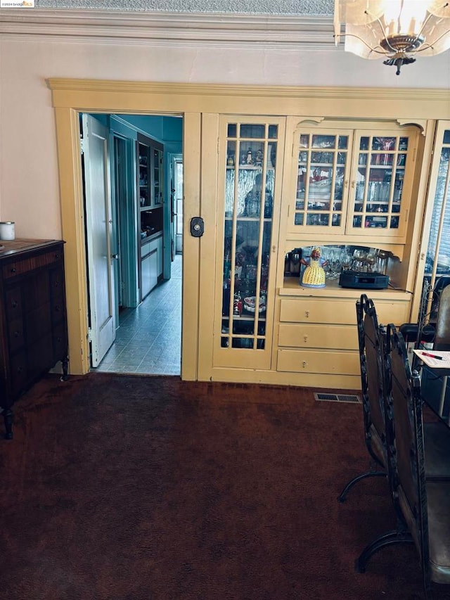 carpeted home office with a notable chandelier, french doors, and crown molding