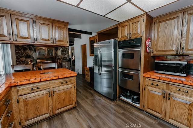 kitchen featuring tile countertops, dark hardwood / wood-style floors, and appliances with stainless steel finishes