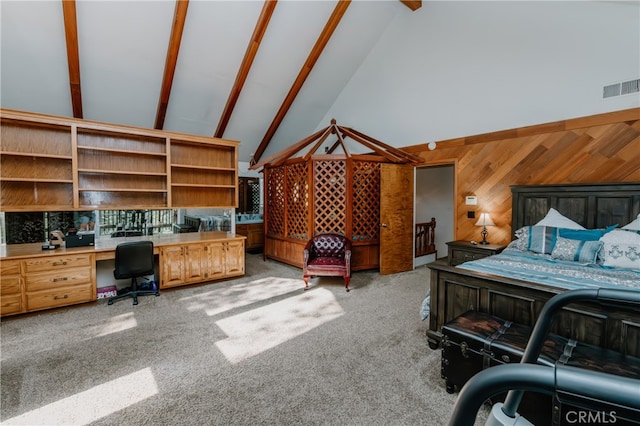 bedroom with light colored carpet, beamed ceiling, built in desk, and wooden walls