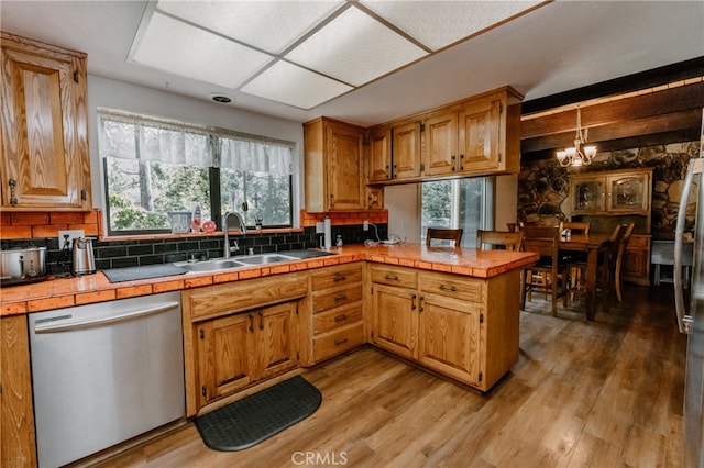 kitchen featuring a healthy amount of sunlight, sink, stainless steel dishwasher, and tile countertops