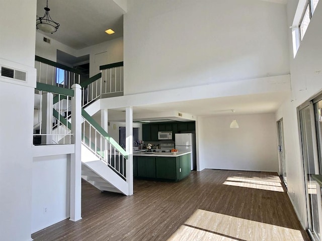 stairway with wood-type flooring and a high ceiling