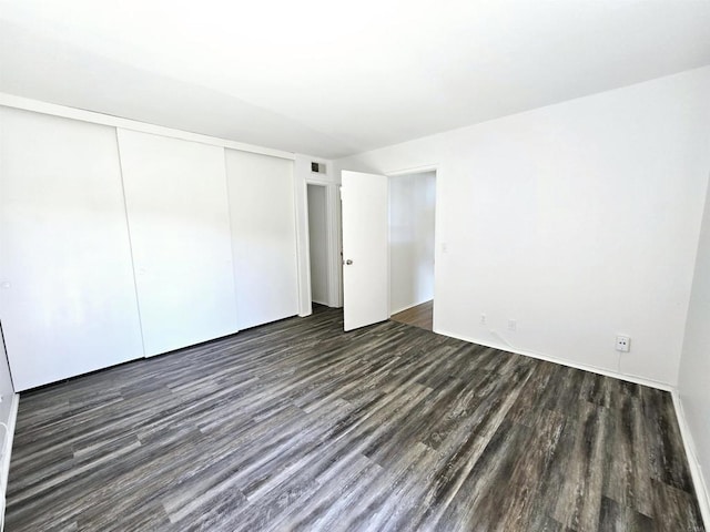 unfurnished bedroom featuring dark wood-type flooring and a closet