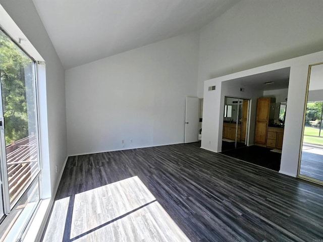 unfurnished living room with vaulted ceiling, plenty of natural light, and dark hardwood / wood-style floors