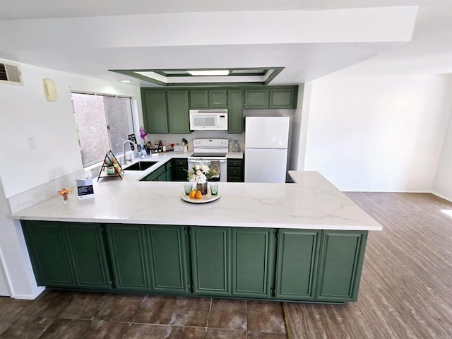 kitchen with kitchen peninsula, green cabinets, a tray ceiling, white appliances, and sink