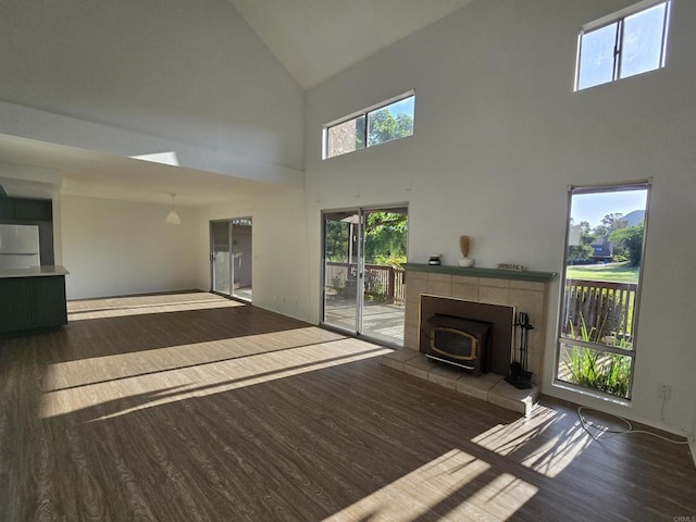 unfurnished living room featuring dark hardwood / wood-style flooring, a wood stove, and high vaulted ceiling