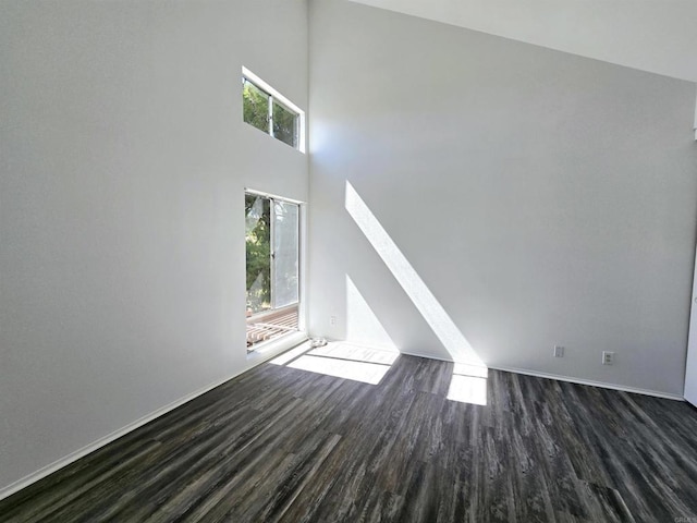 unfurnished living room with dark wood-type flooring and a high ceiling